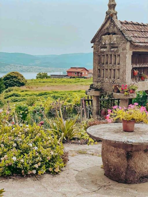 a stone table in a garden with flowers and a building at Casa de campo in Pontevedra