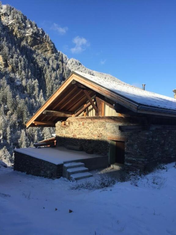 une cabane en rondins dans la neige avec une montagne dans l'établissement Chalet 1829, à Sainte-Foy-Tarentaise