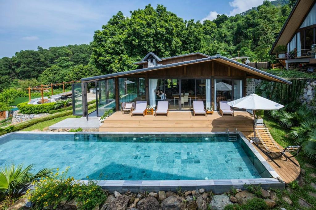 una piscina con terraza y una casa en A Little Hill Retreat, en Hòa Bình