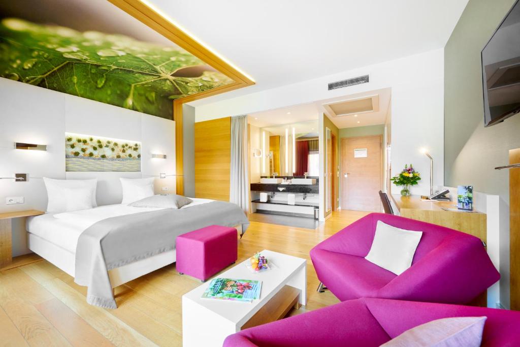 um quarto com uma cama grande e uma cadeira rosa em Kaisergarten Hotel Deidesheim em Deidesheim