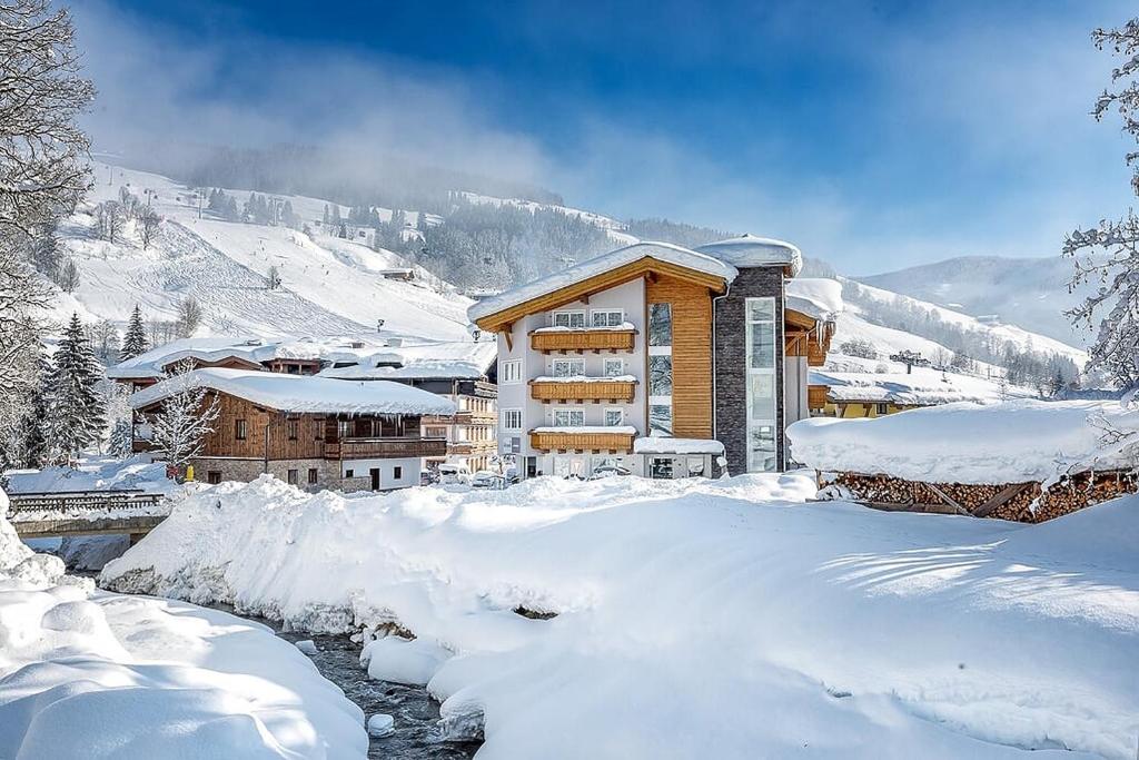 um edifício coberto de neve junto a um rio em Appartements Ferienwohnungen Unser Unterberg em Maria Alm am Steinernen Meer