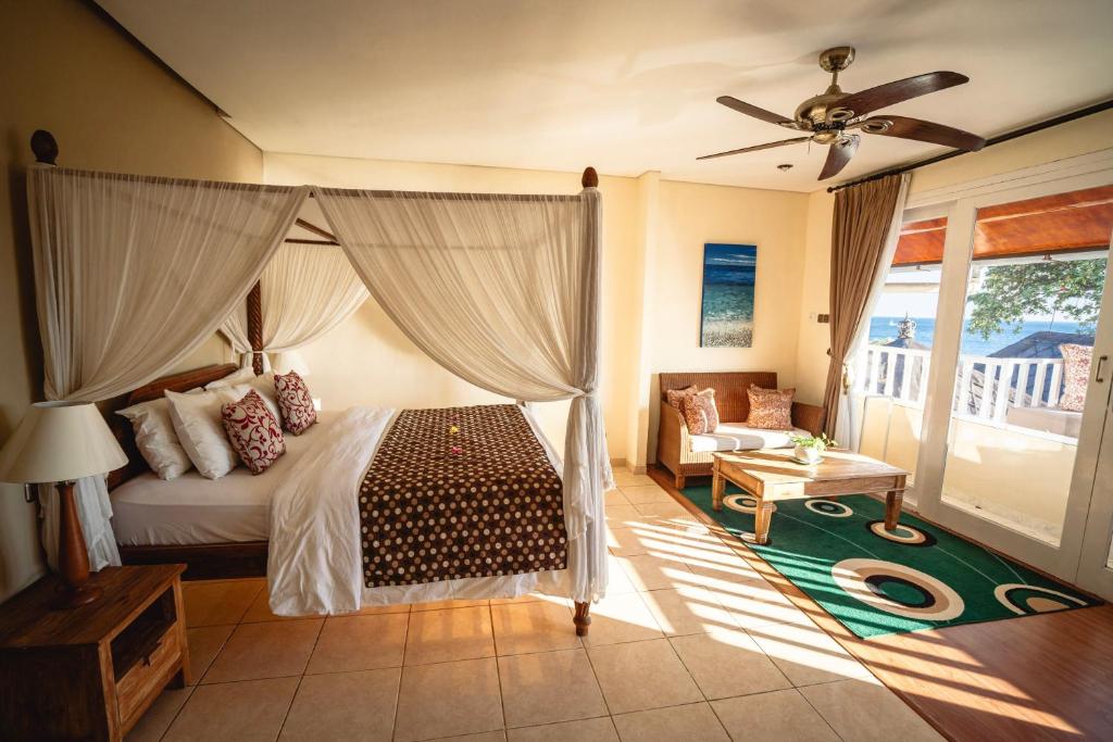 een slaapkamer met een bed en een plafondventilator bij Tauch Terminal Resort Tulamben & Spa in Tulamben