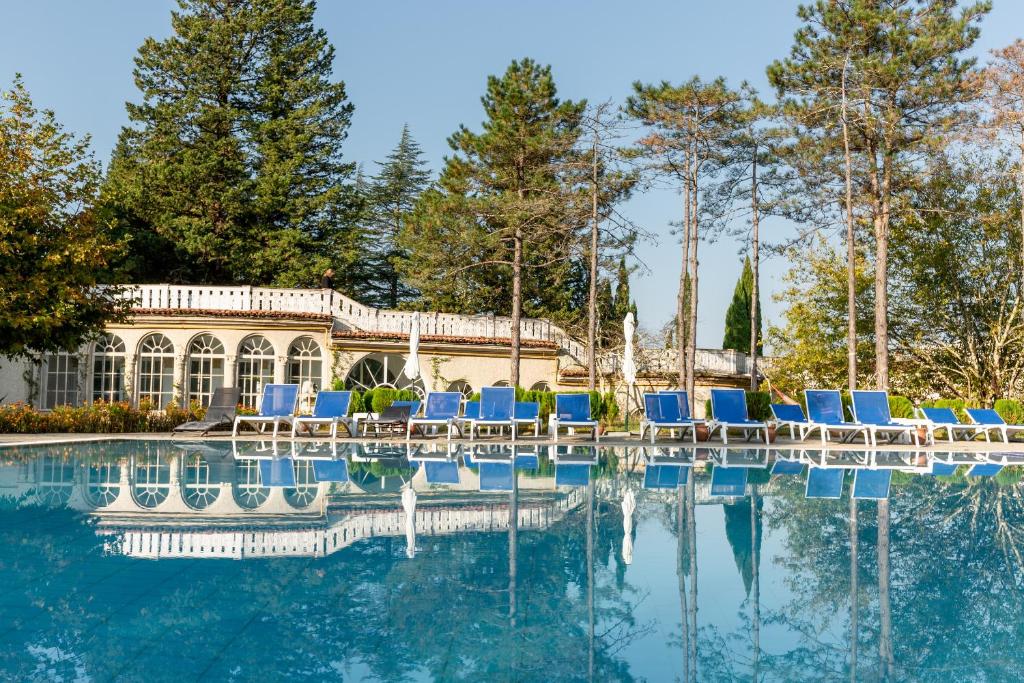 a swimming pool with chairs and a house at Legends Tskaltubo Spa Resort in Tskaltubo