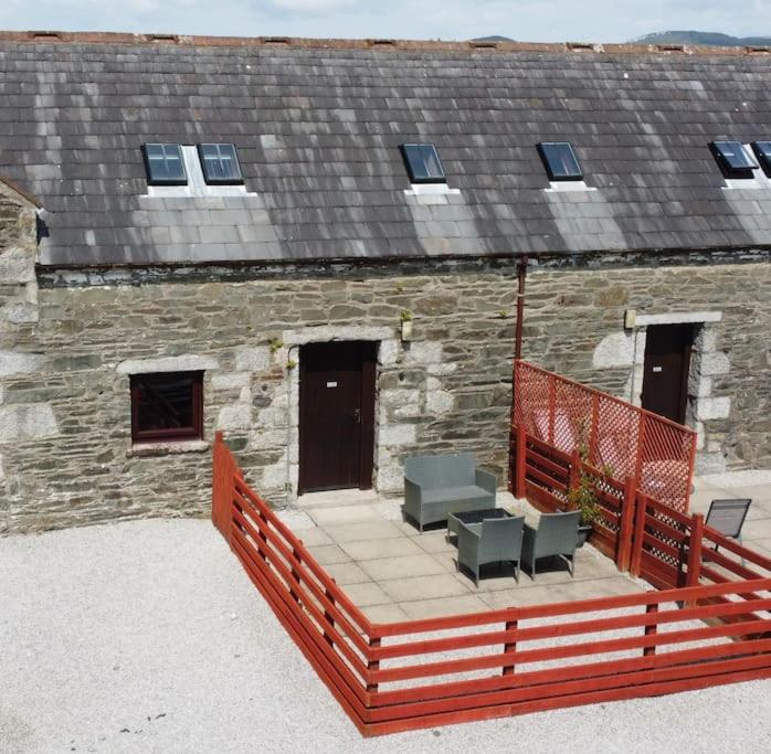 a deck with chairs and a building with a roof at Valley View at Clauchan Holiday Cottages in Gatehouse of Fleet