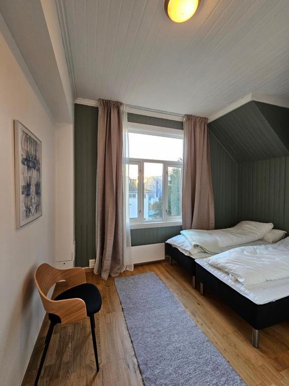 een slaapkamer met een bed, een raam en een stoel bij Lovely city center apartment with amazing views and free parking! in Tromsø