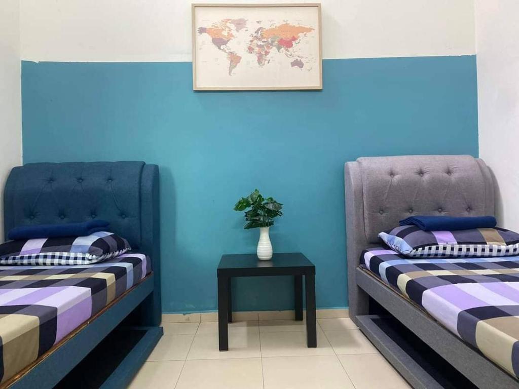 duas camas num quarto com paredes azuis e uma mesa em 3 rooms (aircond) in Muar Town em Muar