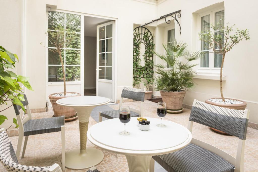 a patio with two tables and chairs and two glasses of wine at Acacias Etoile in Paris