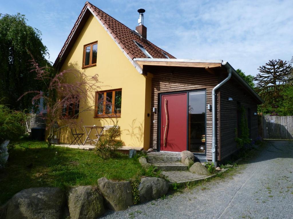mały żółty dom z czerwonymi drzwiami w obiekcie Grüne Oase w Kilonii