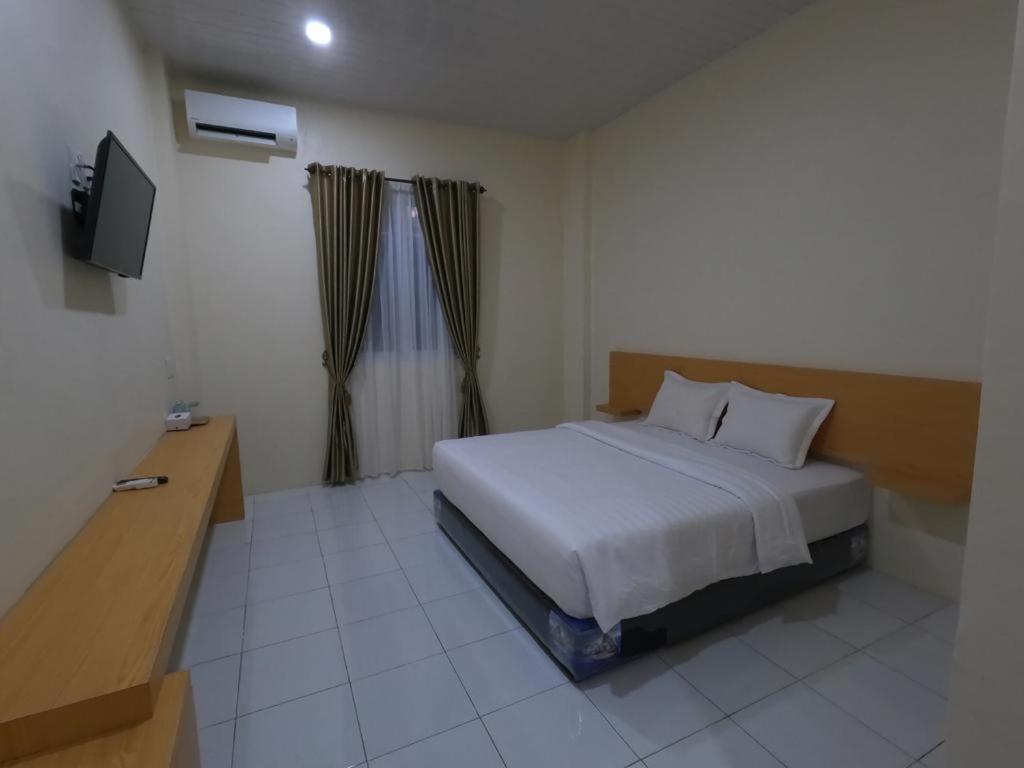 Grand Langkawi hotel aceh في Lheue: غرفة نوم فيها سرير وتلفزيون