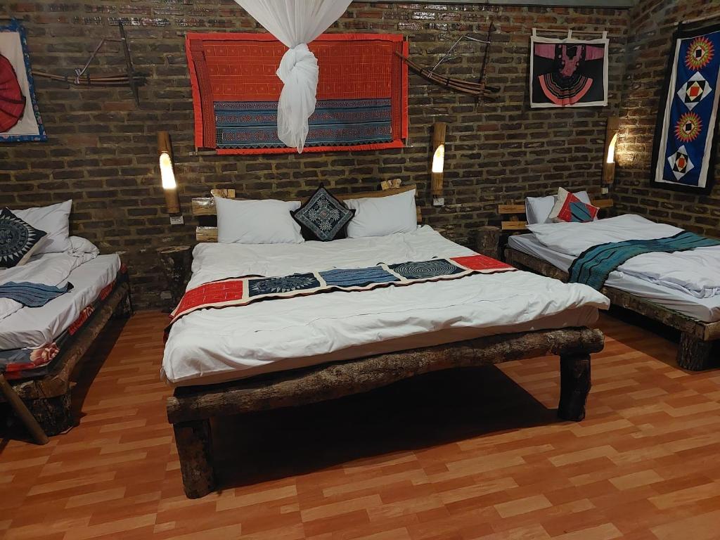 a bedroom with two beds and a brick wall at A La Homestay in Hòa Bình
