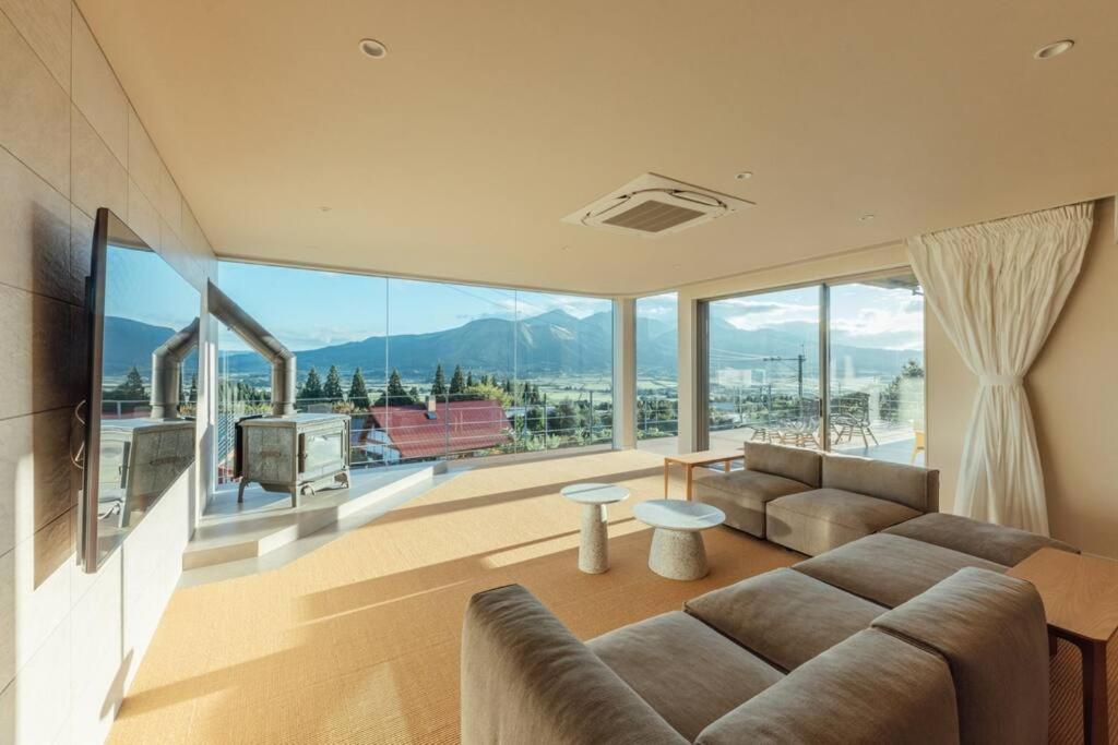 uma sala de estar com um sofá e janelas grandes em asoha em Minami Aso
