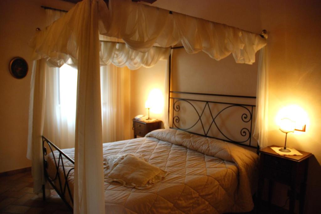 a bedroom with a canopy bed with two lamps at Locanda Le Logge in Urbisaglia