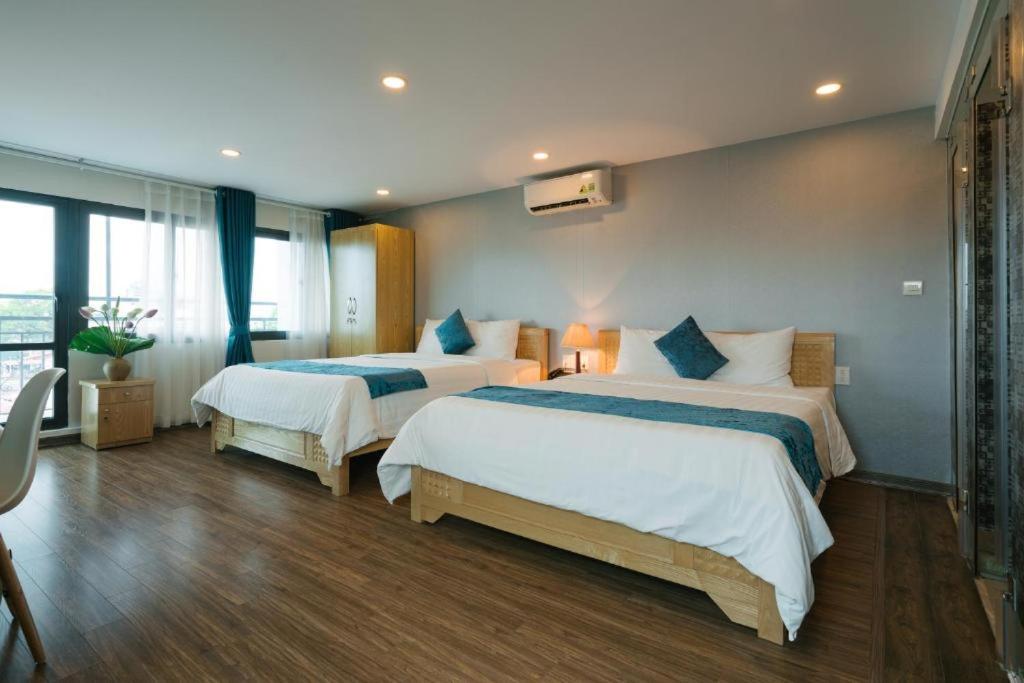 una camera d'albergo con due letti con lenzuola blu e bianche di Hanoi Prime Garden Hotel & Spa a Hanoi
