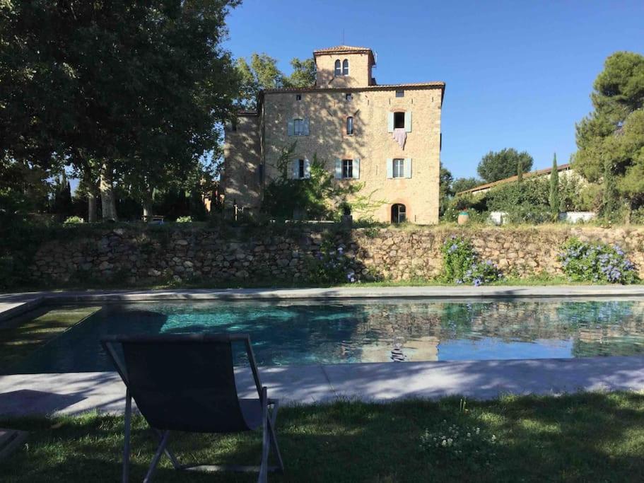 une chaise assise à côté d'une piscine devant un immeuble dans l'établissement Château de Villeclare - 2 nuits minimum, à Palau-del-Vidre