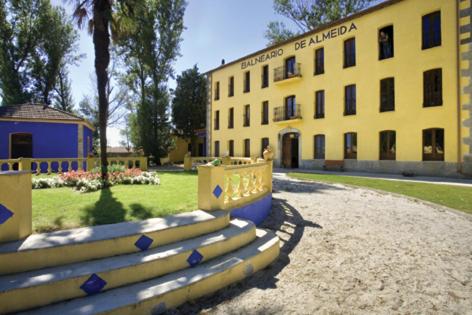 un edificio amarillo con una valla delante en Hotel Balneario Almeida Dama Verde en Almeida de Sayago