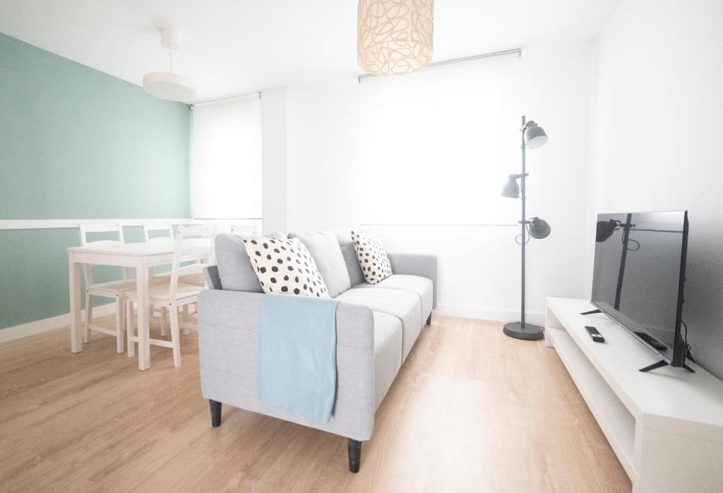 sala de estar con sofá blanco y TV en Apartamento Balbín IV, en Gijón