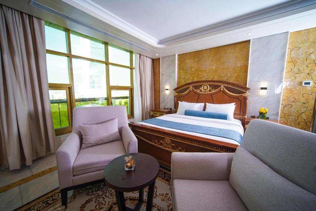 アブダビにあるAG ホテルのベッド1台と椅子2脚が備わるホテルルームです。