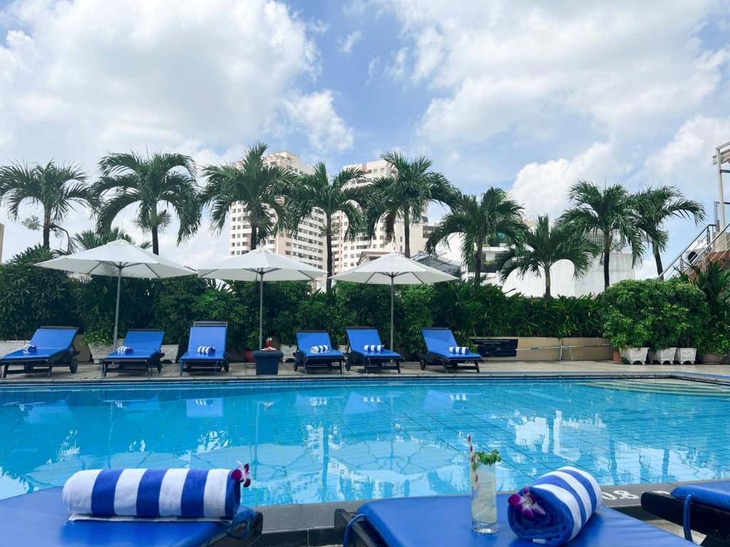 a swimming pool with blue chairs and palm trees at Ramana Saigon Hotel in Ho Chi Minh City