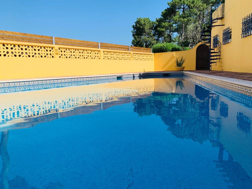 a swimming pool with blue water in front of a yellow building at Fashion Villa in Vilamoura with Private Pool in Quarteira