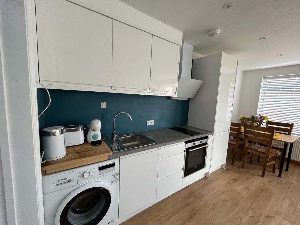 a kitchen with white cabinets and a washing machine at Ecology North London Studios in East Barnet