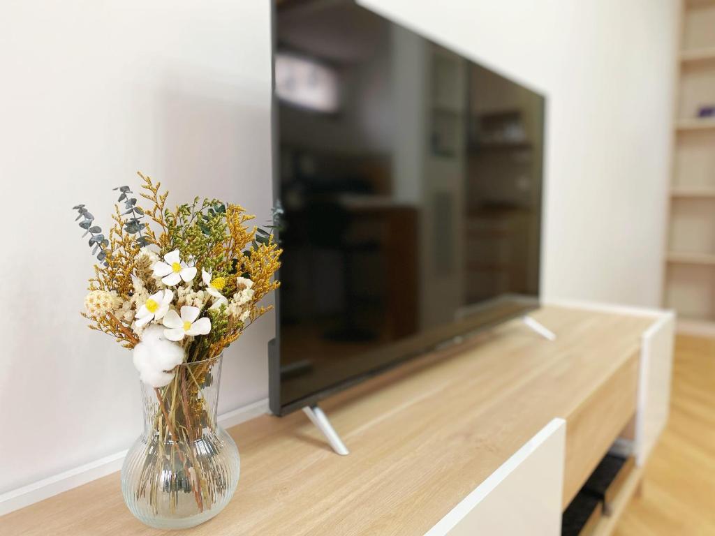 a vase filled with flowers on a table next to a tv at Chez les deux garçons in Montrouge