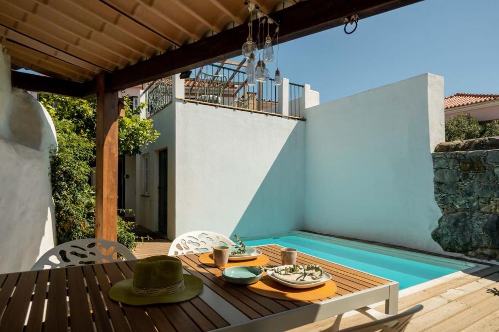 um pátio com uma mesa e cadeiras e uma piscina em Sea´ya Thoughtful Stays - Villa Areia em Cascais