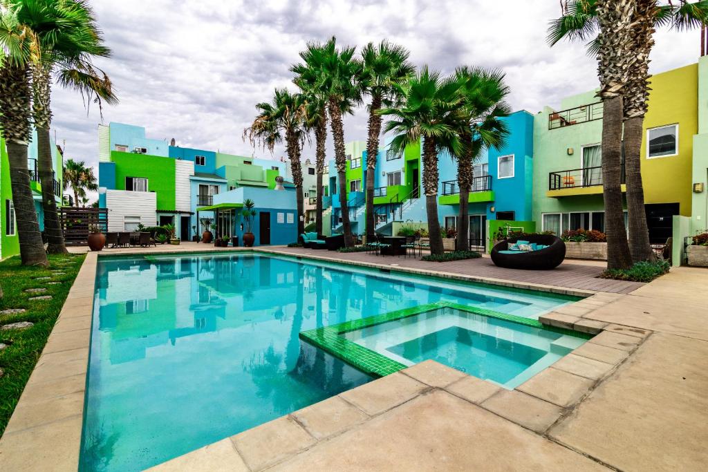a swimming pool in front of a building with palm trees at Rosarito Chic Escape*King Bed*Wi-Fi*Pool*BBQ*3 Gardenhaus in Tijuana