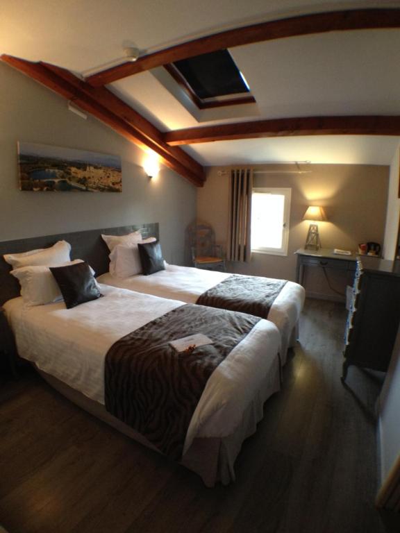 a hotel room with two beds and a window at Logis Hotel Restaurant la Ferme in Avignon