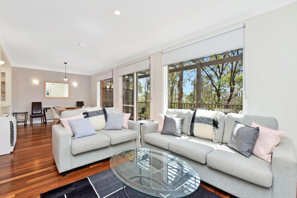 a living room with two couches and a glass table at Villa 2br Albarino Villa located within Cypress Lakes Resort in Pokolbin