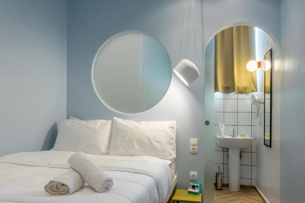 - une chambre avec un lit blanc, un miroir et un lavabo dans l'établissement Cabins Sleeping, à Athènes
