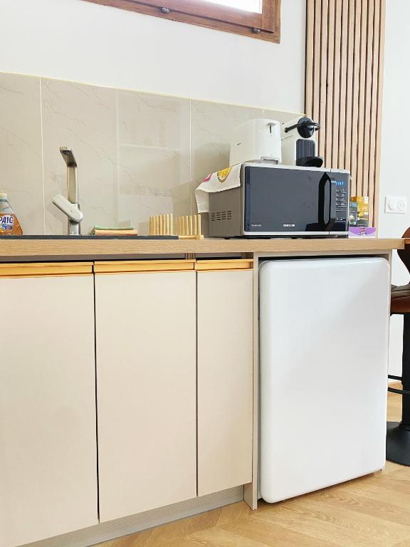 a kitchen with white cabinets and a microwave on a counter at Chez les deux garçons in Montrouge