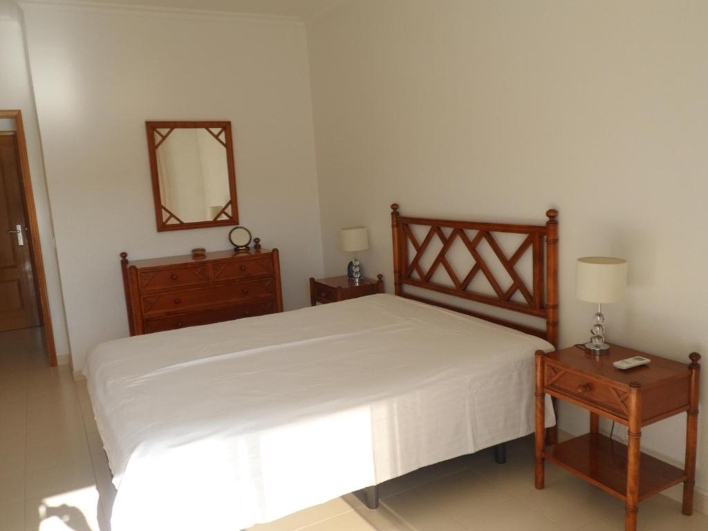 Schlafzimmer mit einem Bett, einer Kommode und einem Spiegel in der Unterkunft Apartamento Varandas do Sol Nascente in Porches