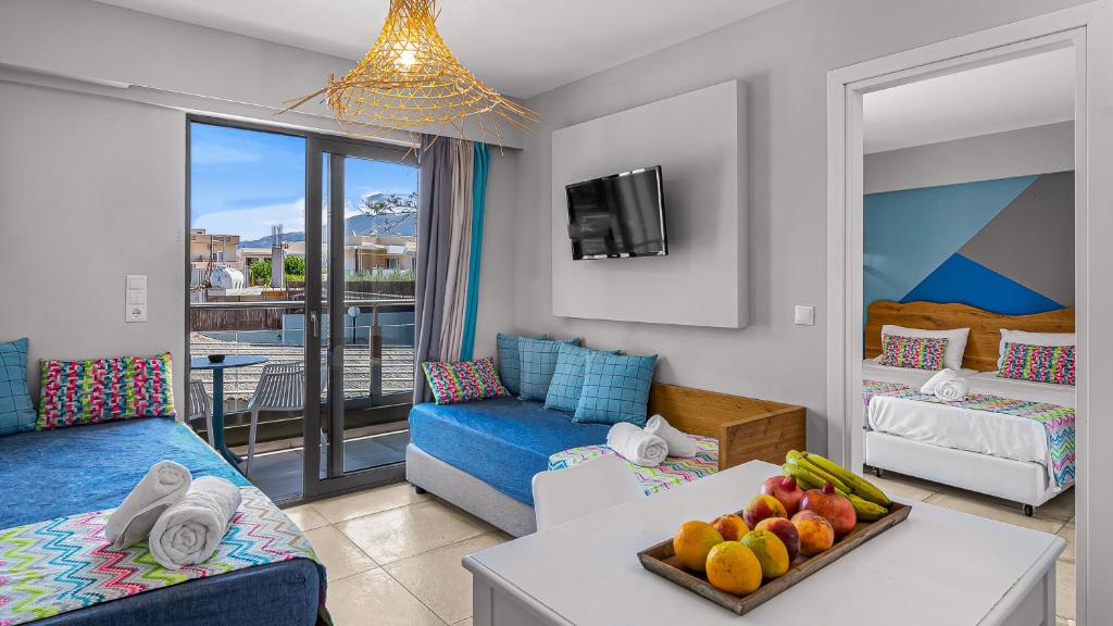 uma sala de estar com um sofá e uma mesa com frutas em Natali Apartments em Mália