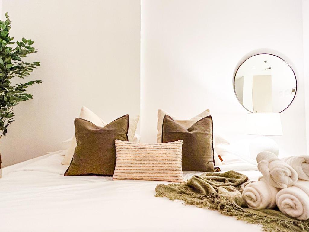 a bedroom with a white bed with pillows and a mirror at Voyage Studio In Waters Edge in Abu Dhabi
