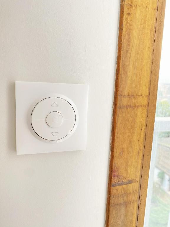 a white lightswitch on a wall next to a window at Chez les deux garçons in Montrouge