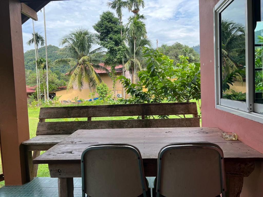 a wooden table and chairs on a porch with a window at Phet Ban Suan Hotel in Ko Chang