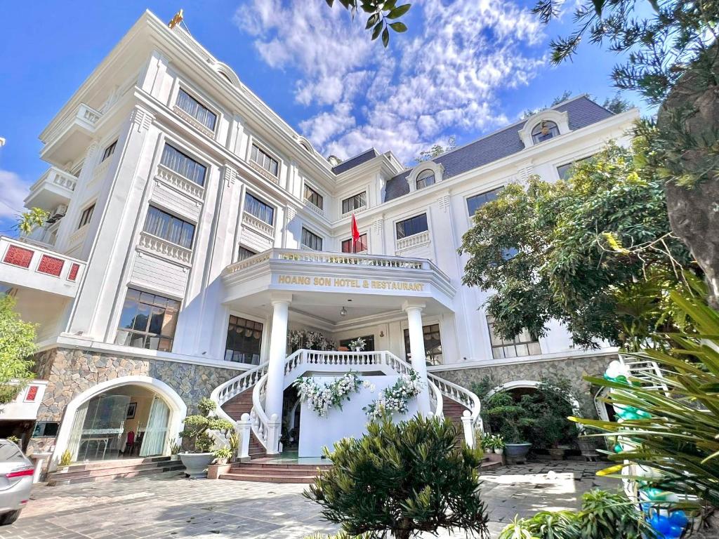 a large white building with a staircase in front of it at Khách sạn Hoàng Sơn in Sơn La