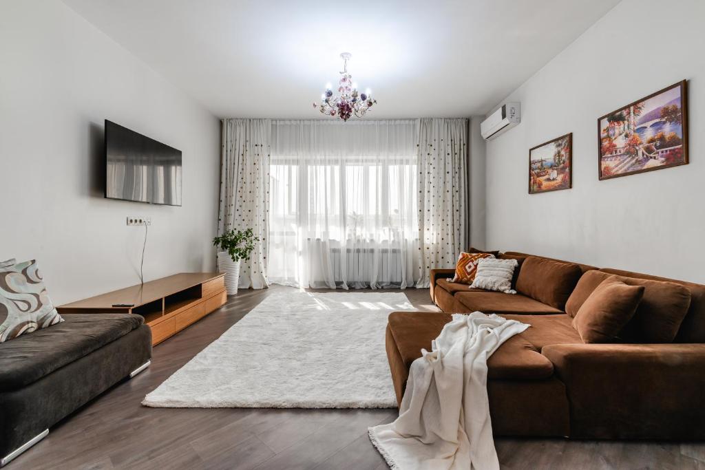 a living room with a brown couch and a tv at Aray apartment in Almaty