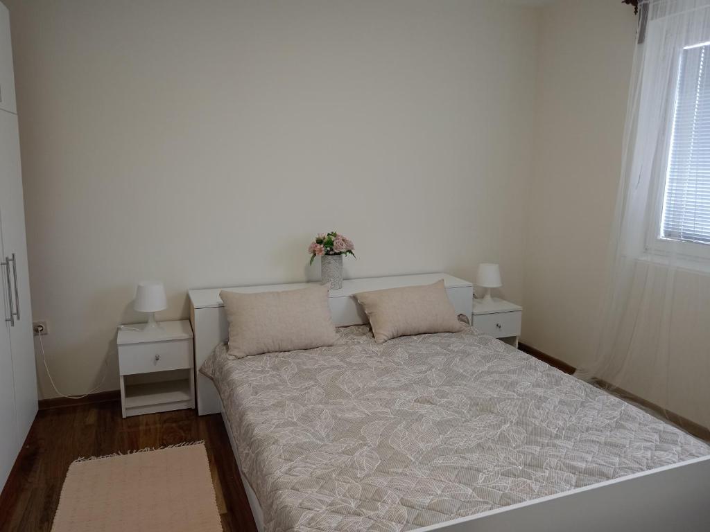 1 dormitorio con 1 cama con 2 almohadas y ventana en Karic apartman, en Paraćin