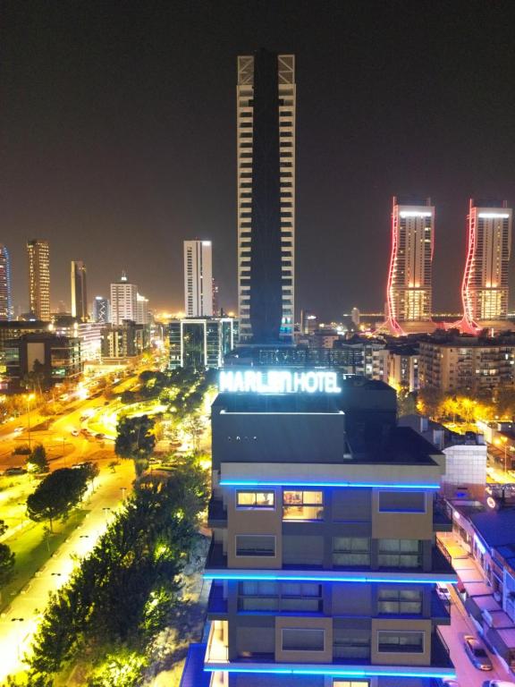 een skyline van de stad 's nachts met een hoog gebouw bij Marlen Hotel Bayraklı in Bayrakli