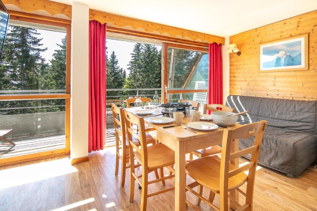 a dining room with a table and chairs and a couch at Au Bon Air - Appt au pied des pistes in Chamrousse