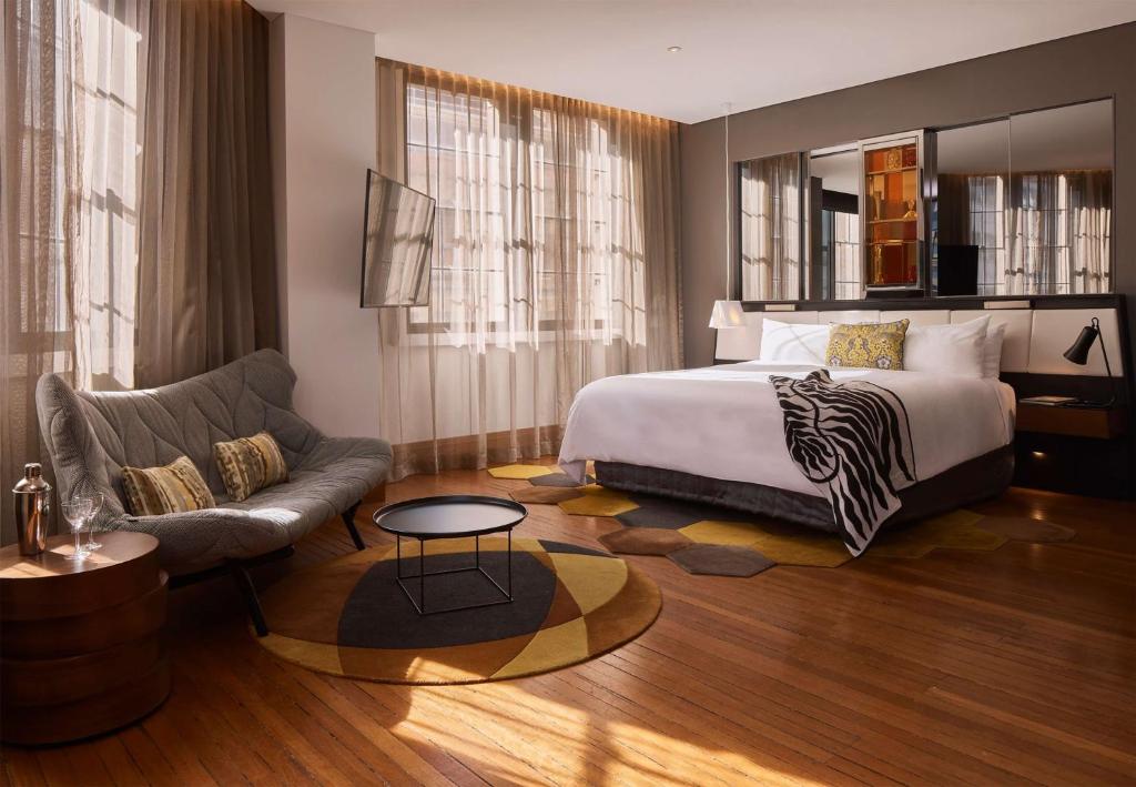 une chambre d'hôtel avec un lit et un canapé dans l'établissement QT Sydney, à Sydney