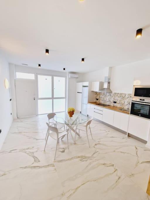 a white kitchen with a glass table and chairs at Exclusivo y único apartamento in Valencia