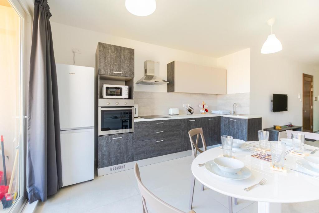 eine Küche mit einem weißen Tisch und Stühlen sowie eine Küche mit einem Kühlschrank in der Unterkunft Brand New Apartment 3Bdr 2 Bth H11 in St Paul's Bay