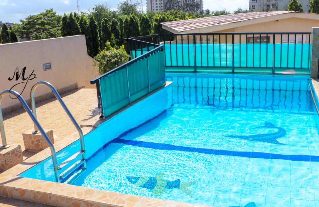 a large swimming pool with a blue fence and stairs in it at Mei Place Apartments in Mombasa