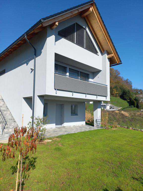 a white house with a balcony and a yard at Lauda i bric in Mirna