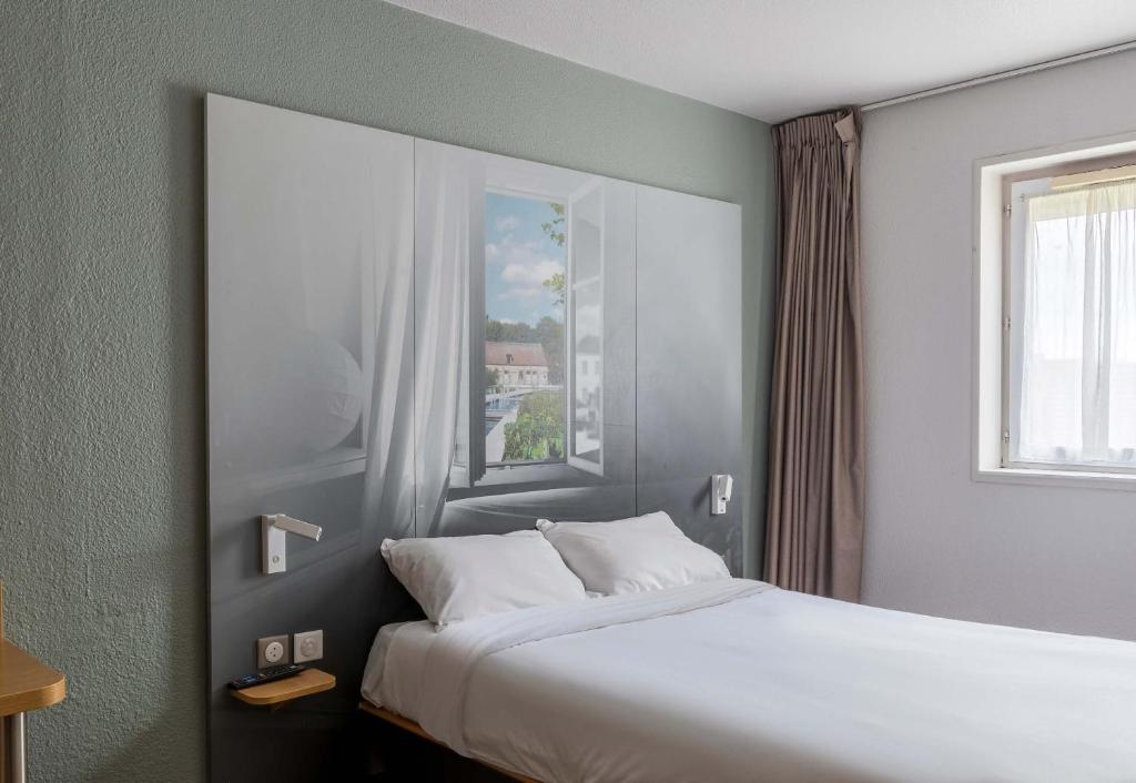 um quarto com uma cama grande e uma janela em B&B HOTEL Troyes Saint-Parres-aux-Tertres em Saint-Parres-aux-Tertres