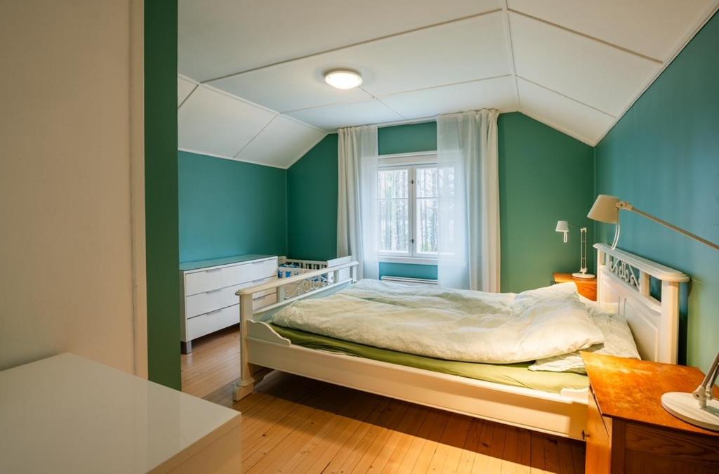 a bedroom with a bed with green walls and a window at Skomakerhuset in Løten