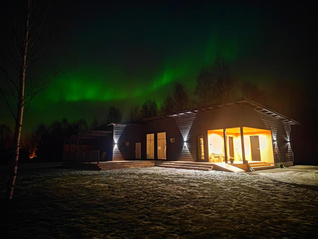 een huis met het noorderlicht in de lucht bij Villa Pajunkissa in Rovaniemi