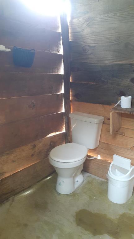 a bathroom with a toilet in a wooden wall at Chales sprinfeld in Paraty